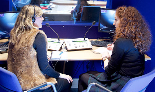 Two people sat in a microphone booth.